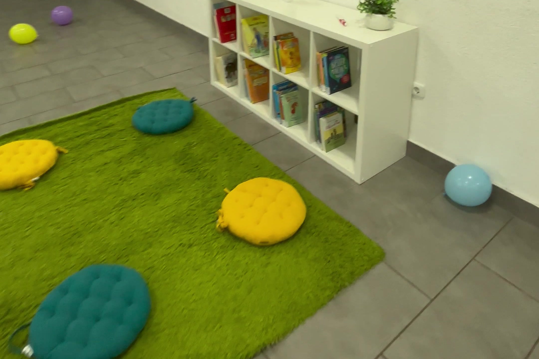Gemütliche Leseecke mit grünem Teppich, Sitzkissen und Bücherregal in der Lernovus Akademie Hanau
